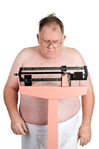 Uomo obeso che si pesa
